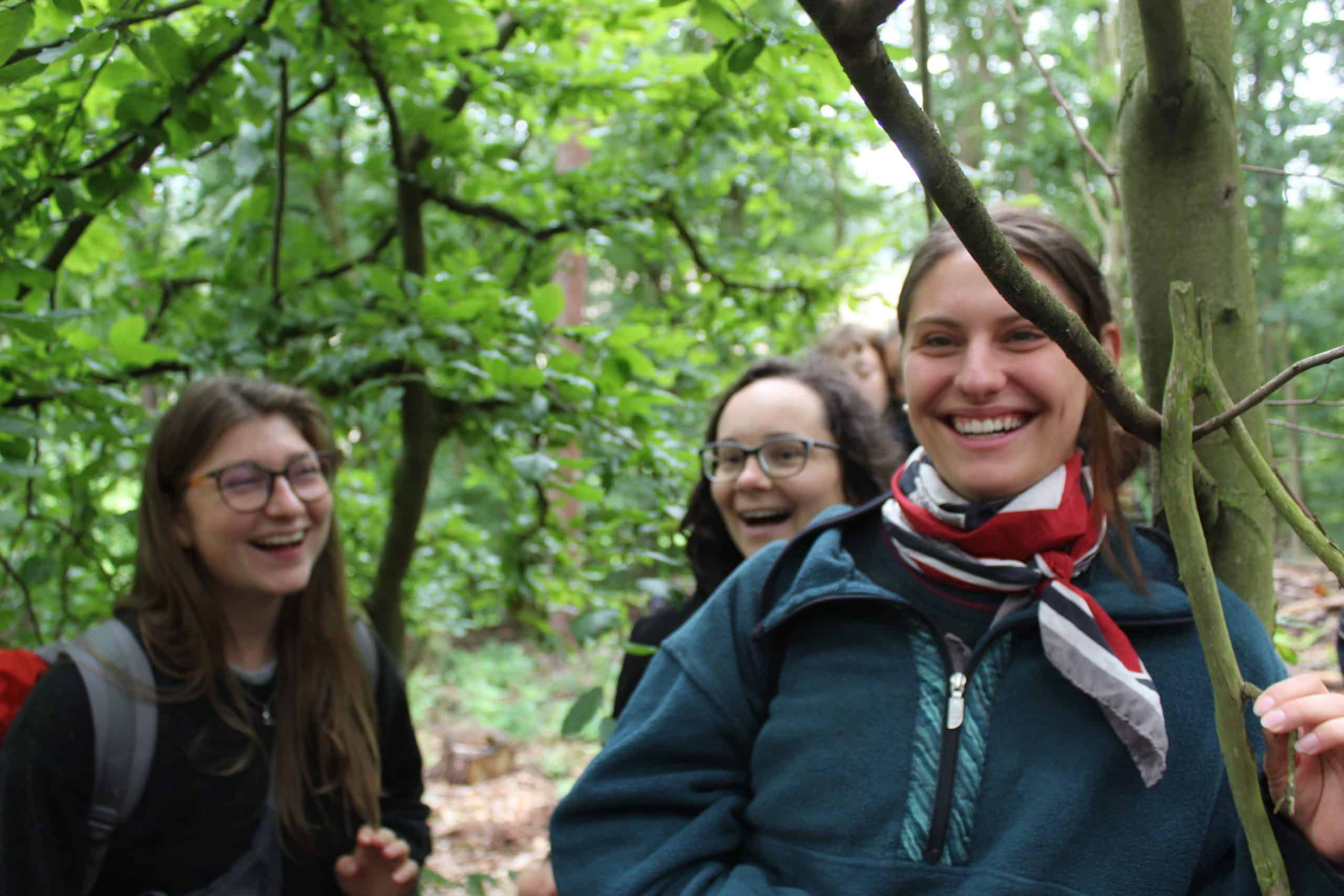 Drei junge Frauen stehen lachend im Wald &ndash; Gemeinschaft, Freude und Naturerleben